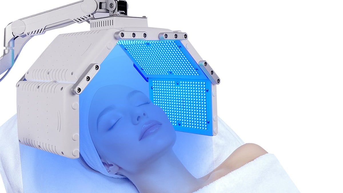 Client under a blue-light LED PDT dome during a professional treatment session